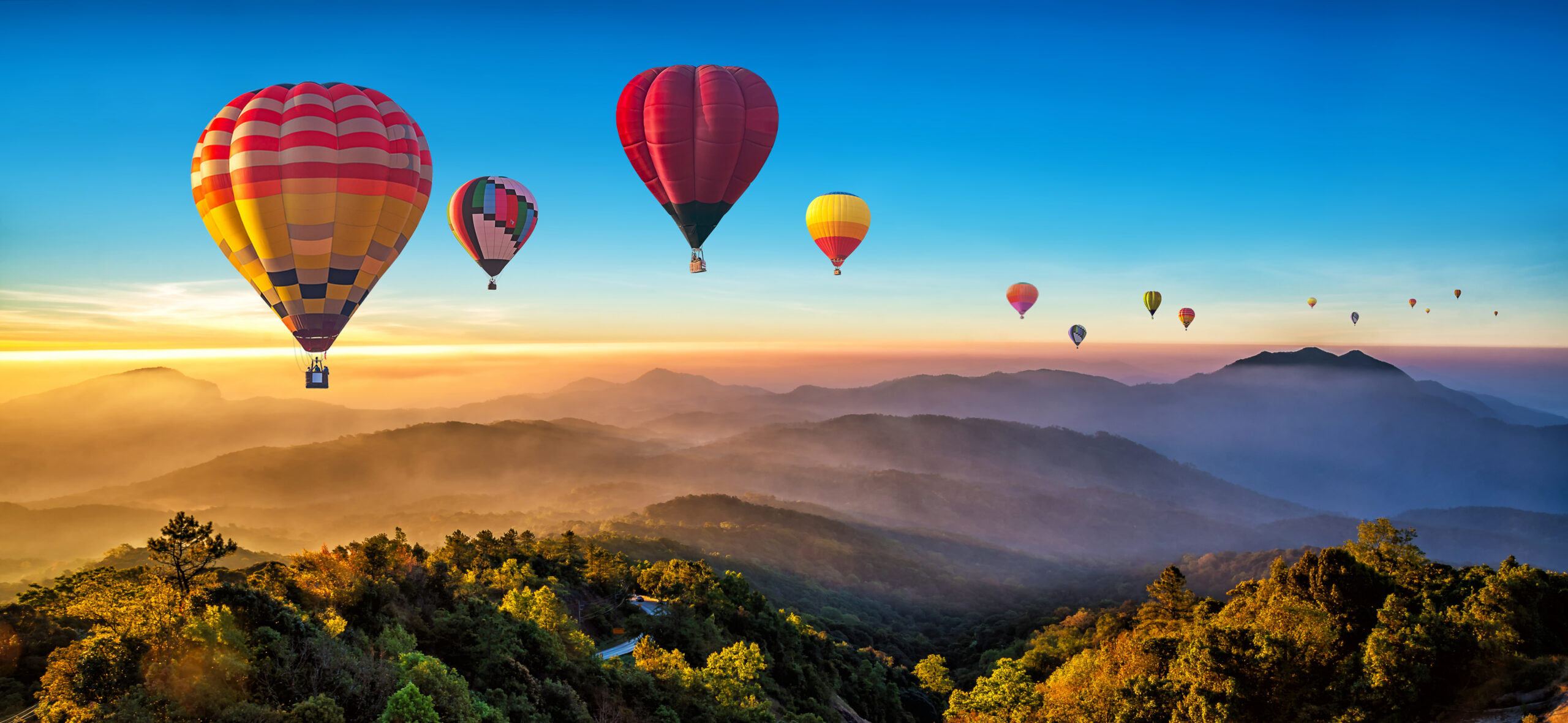 Colorful hot air balloons flying over mountain